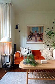 a living room filled with furniture and a painting on the wall above it's coffee table