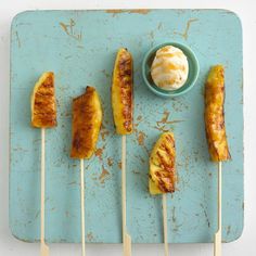 several skewers of food sitting on top of a blue table next to a bowl of ice cream