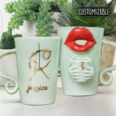 two coffee mugs with designs on them sitting next to succulents and cacti