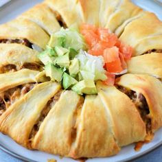 a white plate topped with meat and veggies covered in pastry crusts on top of a blue table cloth