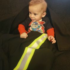 a little boy sitting on top of a black couch next to a neon green tie