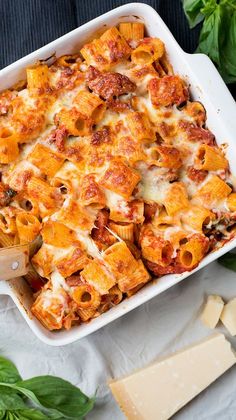 a casserole dish filled with pasta, cheese and spinach on a table