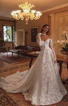 a woman in a white wedding dress standing next to a table and chandelier