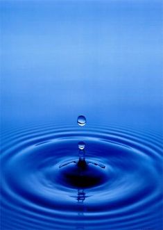 a blue water droplet in the middle of a body of water with ripples