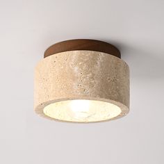 a light that is on the ceiling with a white wall behind it and a wooden base