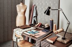 an assortment of crafting supplies on a table next to a lamp and mannequin