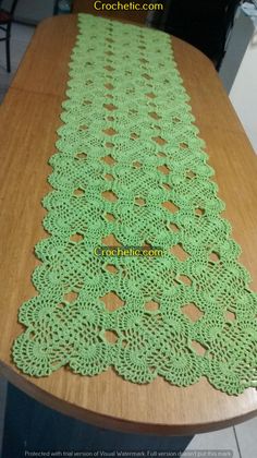 the table runner is made with green crocheted doily on top of a wooden table