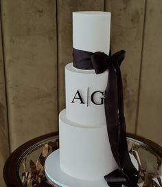 a three tiered white cake with a black ribbon on the top that says aig