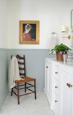 a chair in a bathroom with a painting on the wall