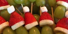 some grapes and strawberries are arranged on sticks with santa's hats on them