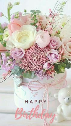 a vase filled with lots of flowers on top of a wooden table next to a teddy bear