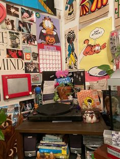 there is a record player on the table in front of many pictures and posters hanging on the wall