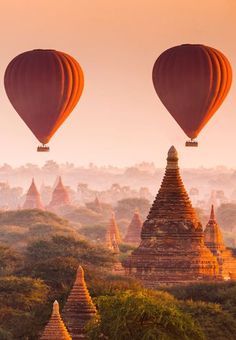 two hot air balloons flying over temples in the sky