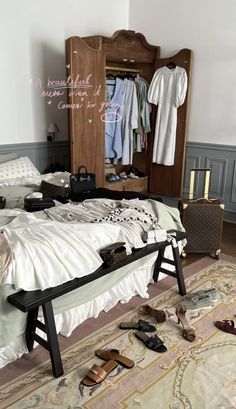 an unmade bed with shoes on the floor next to it and a wardrobe behind it