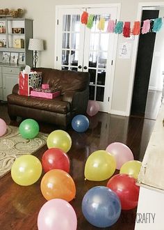 a living room filled with lots of balloons on top of a hard wood floor next to a brown couch