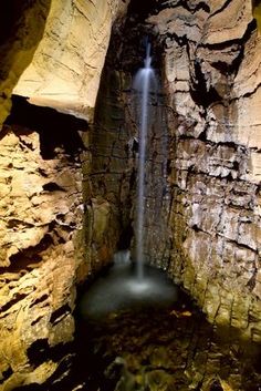 a small waterfall in the middle of a cave with water coming from it's mouth