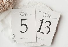 two place cards with the number thirteen on them next to some dried flowers and leaves