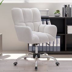 a white office chair sitting in front of a book shelf