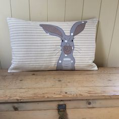 a pillow with a rabbit on it sitting on top of a wooden bench next to a chest