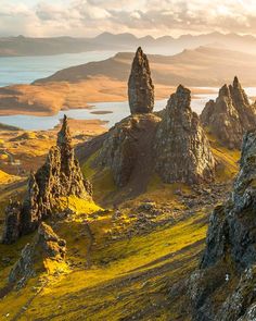 the mountains are covered in green grass and rock formations, with water in the distance