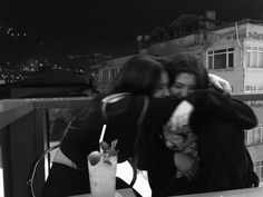 two people hugging each other on a balcony at night