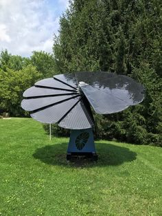 a large satellite dish sitting in the middle of a green field next to some trees