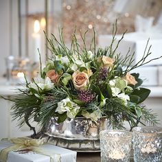 a vase filled with flowers sitting on top of a table next to candles and presents