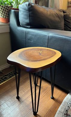 a wooden table sitting on top of a hard wood floor next to a black couch