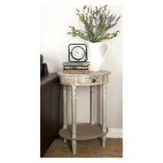 a small table with a clock on it and some flowers in a vase next to it