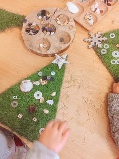 two children are making christmas trees out of buttons and fake grass on a table with other items