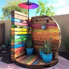 an outdoor shower made out of pallet wood with cactus and succulents