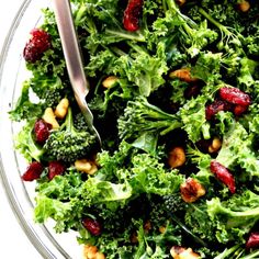 a salad with broccoli, cranberries and nuts in a glass bowl