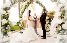 a bride and groom standing under an arch with flowers on it at their wedding ceremony