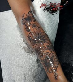 a woman's arm with flowers and butterflies tattooed on the side of her arm