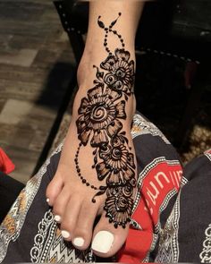 a woman's foot with henna tattoos on it