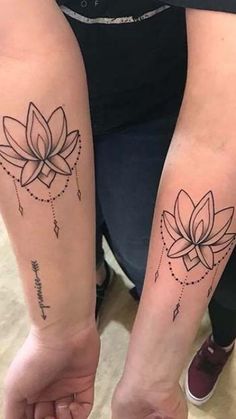 two people with matching tattoos on their arms holding each other's hands and one has a lotus tattoo on it