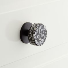 a black and white door knob on a white cabinet with an abstract design in the center