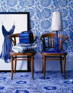 two wooden chairs sitting next to each other in front of a blue and white wall