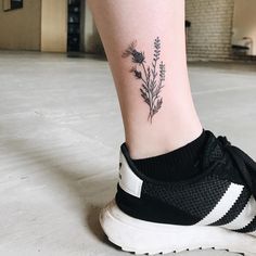 a close up of a person's foot with a flower tattoo on the ankle