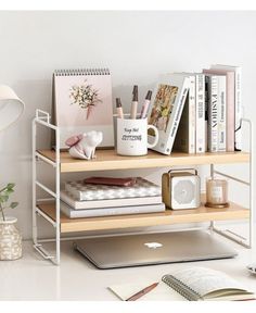 a laptop computer sitting on top of a wooden shelf next to books and other items