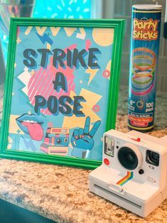 a polaroid camera sitting on top of a counter next to a sign that says strike a pose