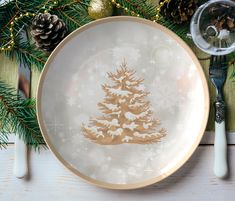 a white plate with a christmas tree on it next to pine cones and silverware