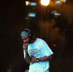 a man with headphones on standing in front of a microphone and holding a microphone up to his mouth