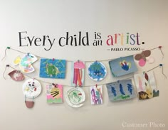 there is a sign on the wall that says every child is an artist and has pictures hanging from it