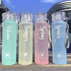 three water bottles sitting next to each other on a wooden table near a building and blue sky