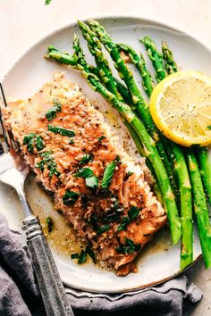 a white plate topped with fish and asparagus