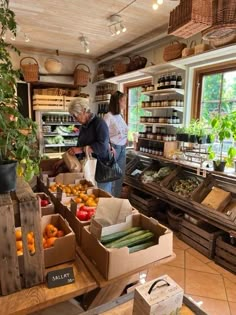 two people standing in a store with boxes of fruit and veggies on the counter