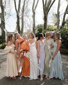 a group of women standing next to each other wearing dresses and holding bouquets in their hands