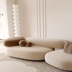 a living room filled with furniture next to a white vase and window sill on the wall