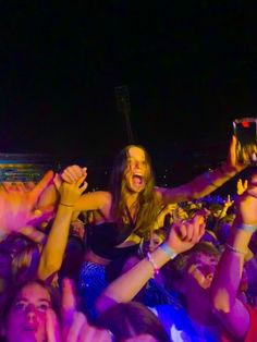 a group of people at a concert with their hands in the air and one person holding up a cell phone